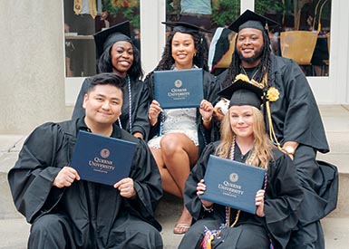 Five graduating students posing with diplomas